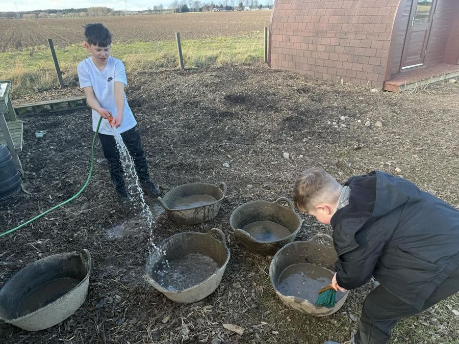 Two young helpers filling buckets with water