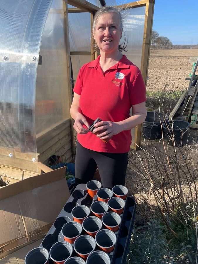 Lesley holding seed trays in the polytunnel