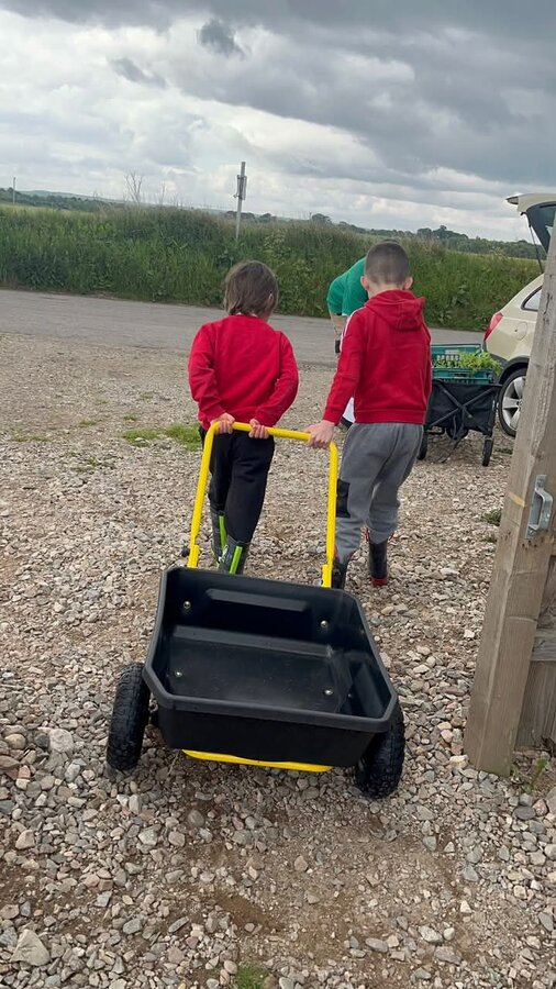 Sharing the burden, pushing the cart together to the polytunnel